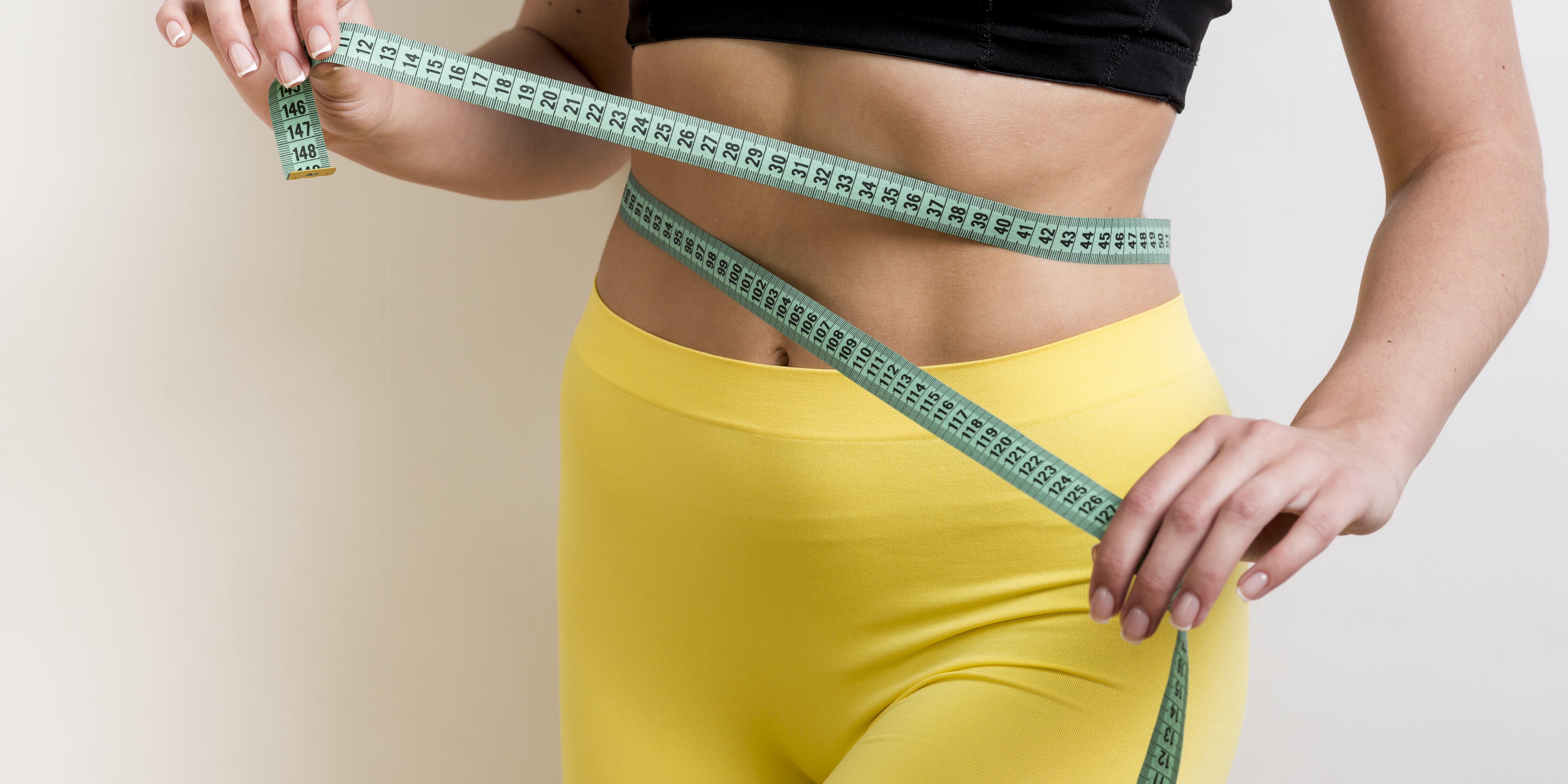 Девушка мерит талию после тренировки