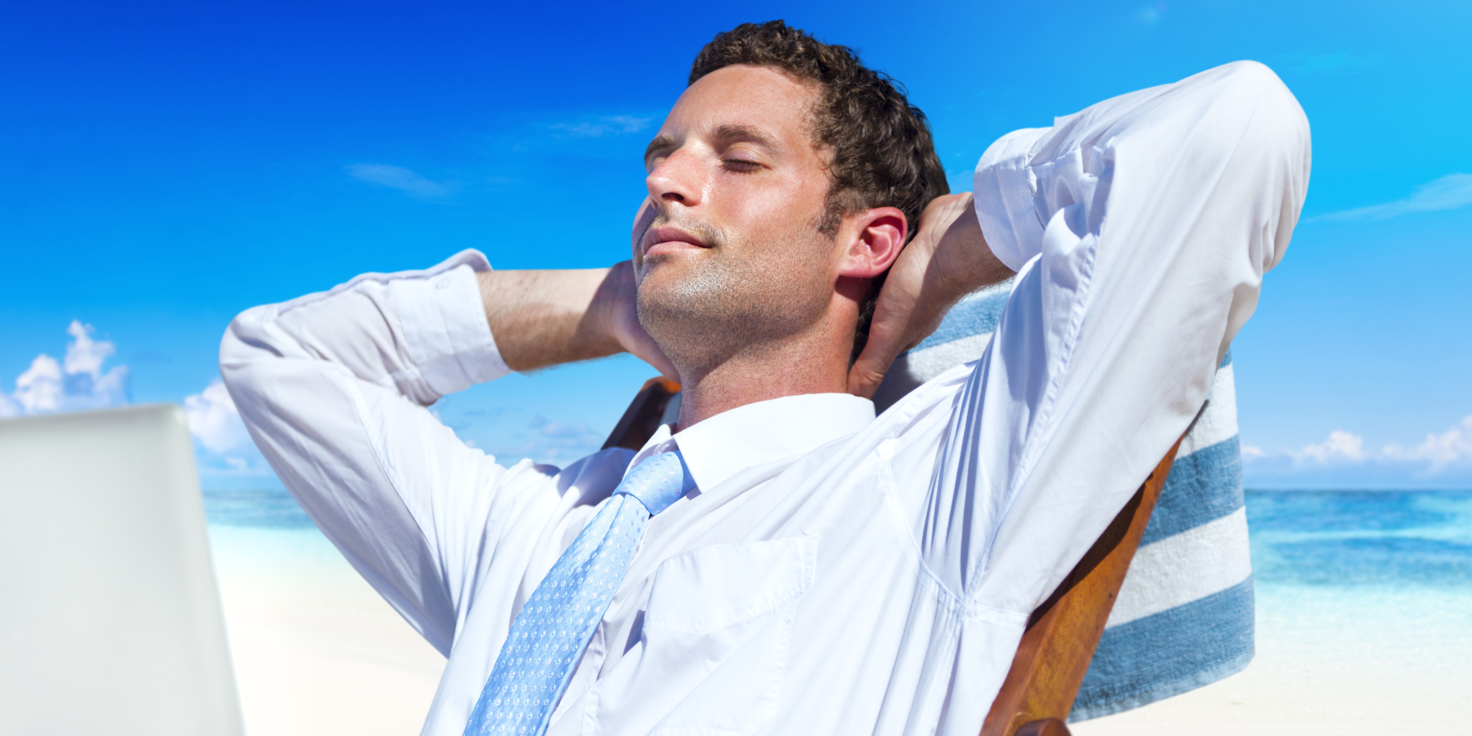 Мужчина с ноутбуком представляет как расслабляется на пляже