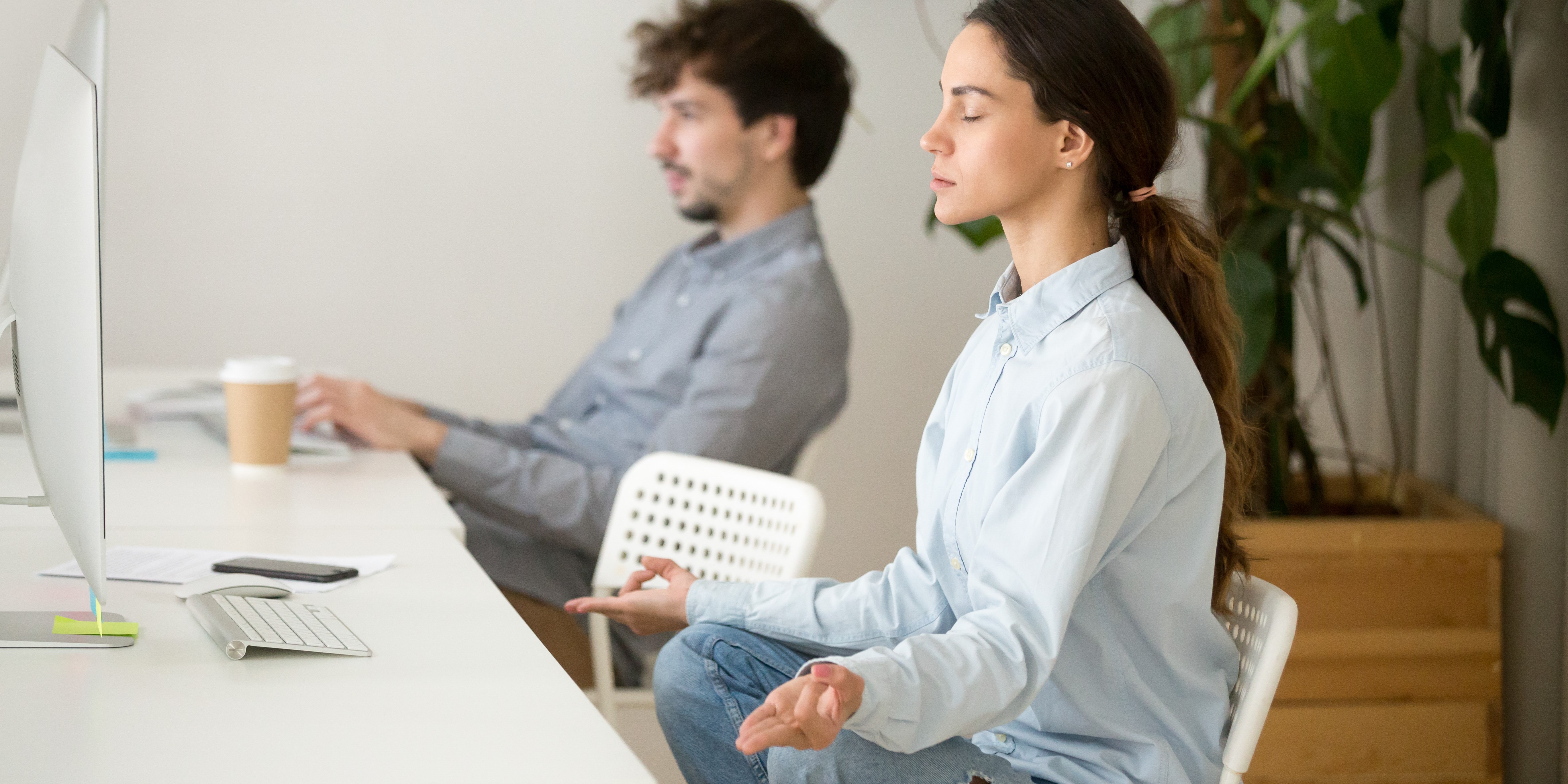 Внимательная спокойная молодая женщина делает перерыв в офисе для медитации