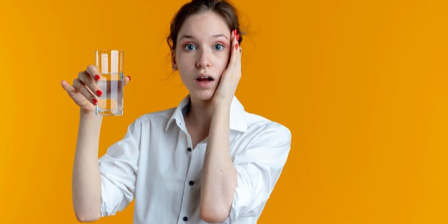 Молодая девушка держит стакан с водой