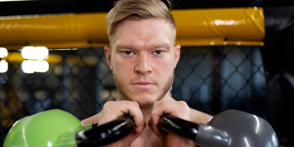 Мужчина, вид спереди, тренируется с гирями