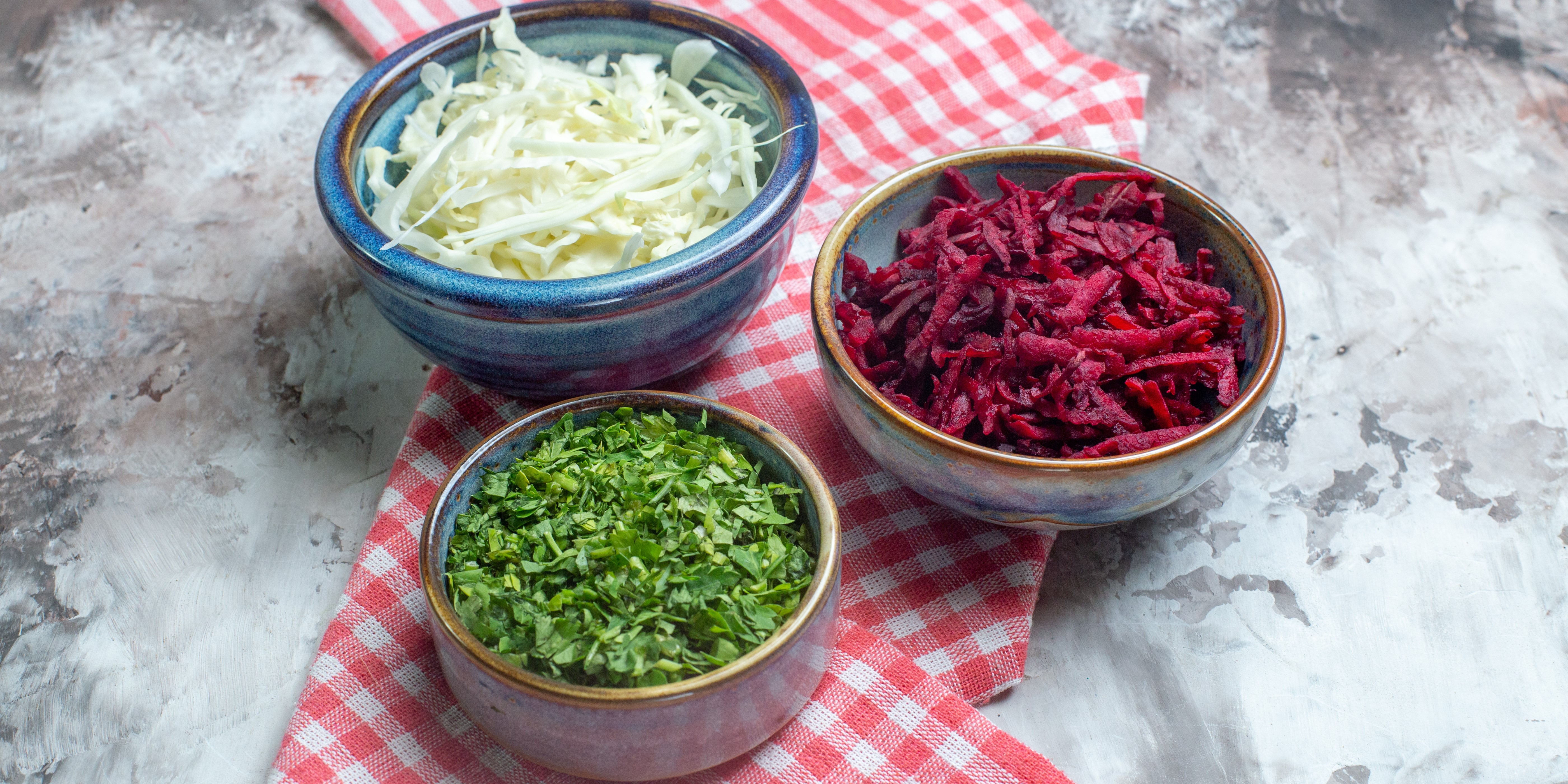 Нарезанная капуста со свеклой и зеленью на белом столе, вид спереди