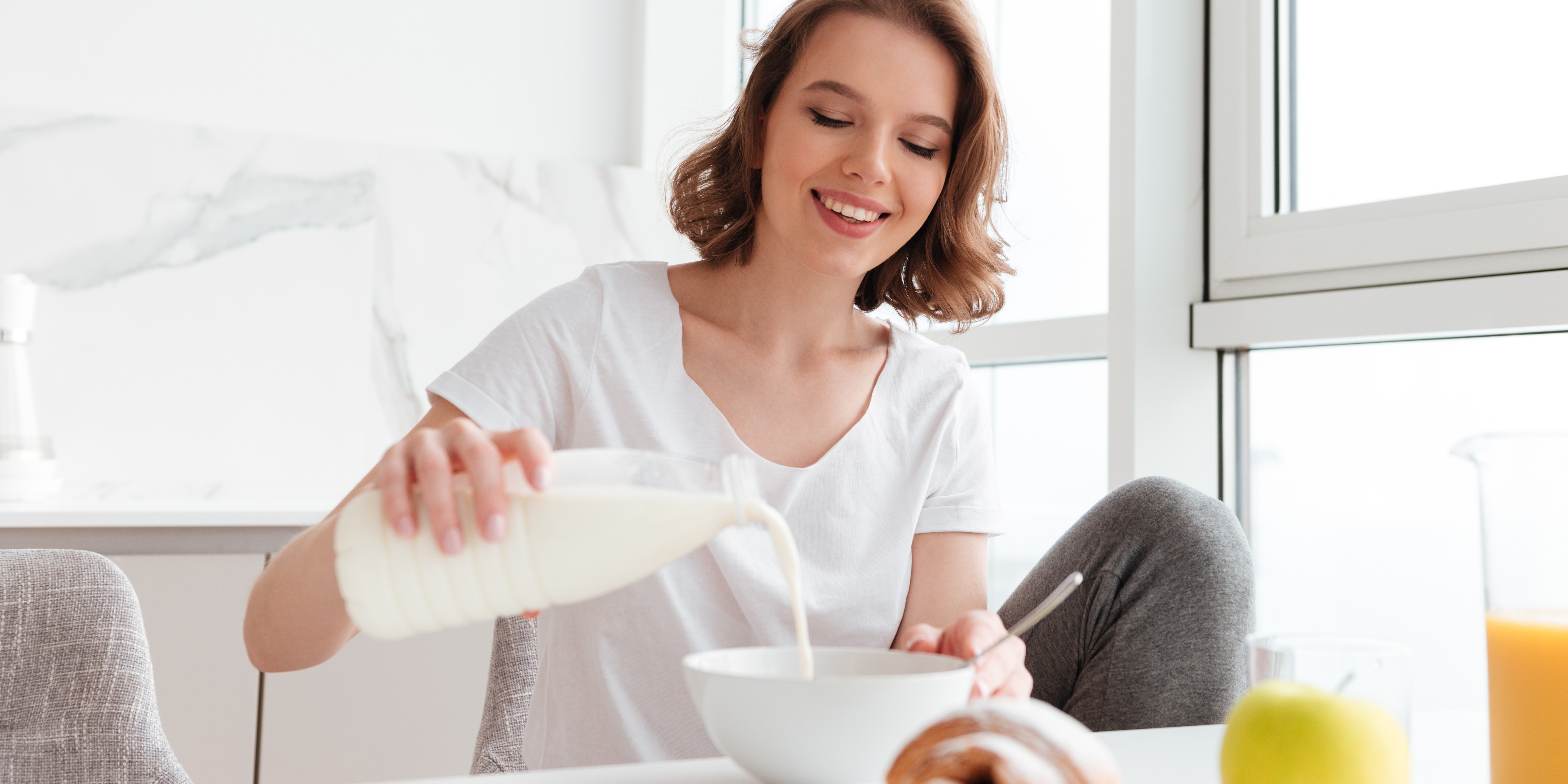 Красивая девушка наливает кефир в миску