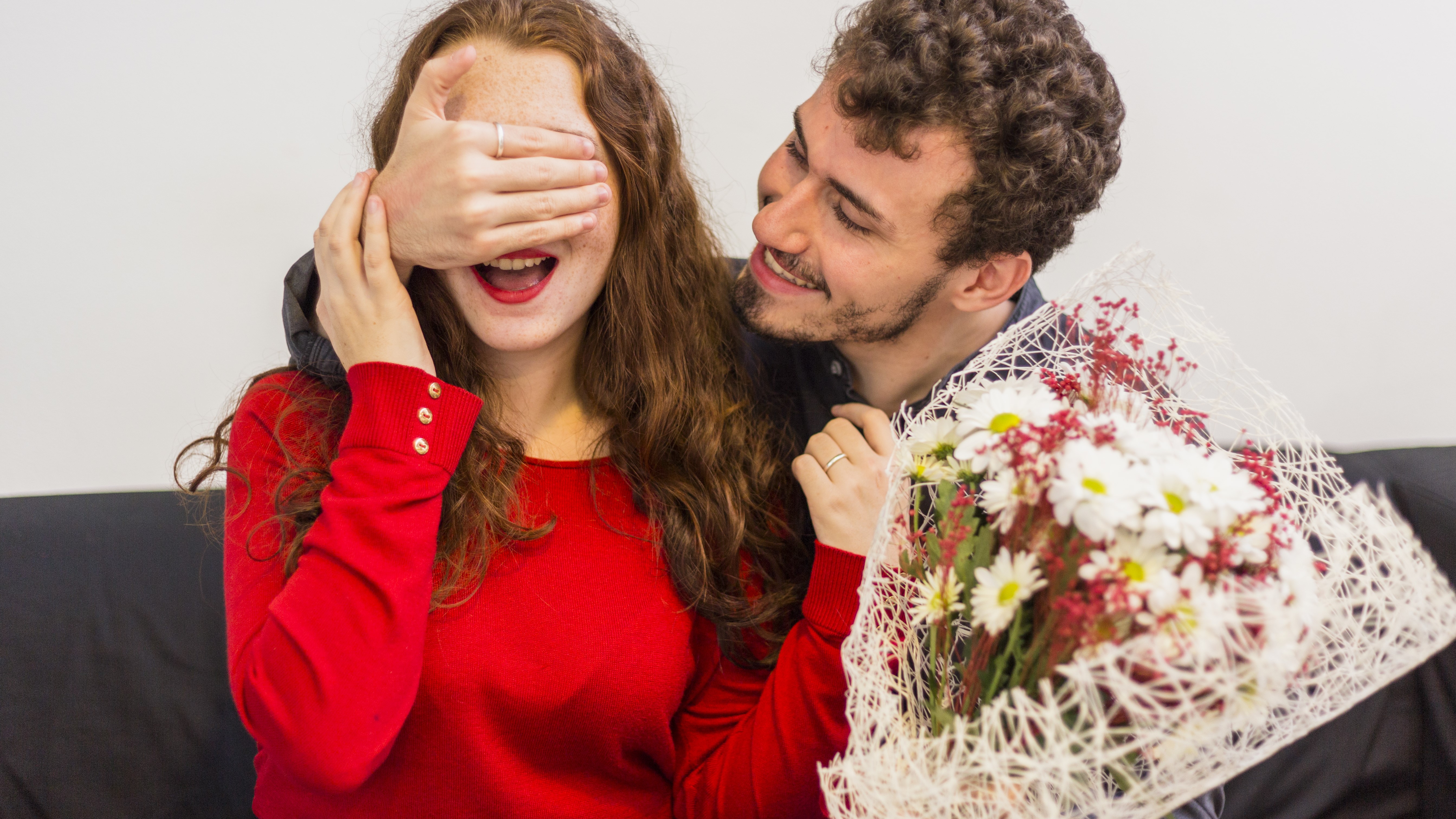 Мужчина нежно прикрывает глаза у своей девушки