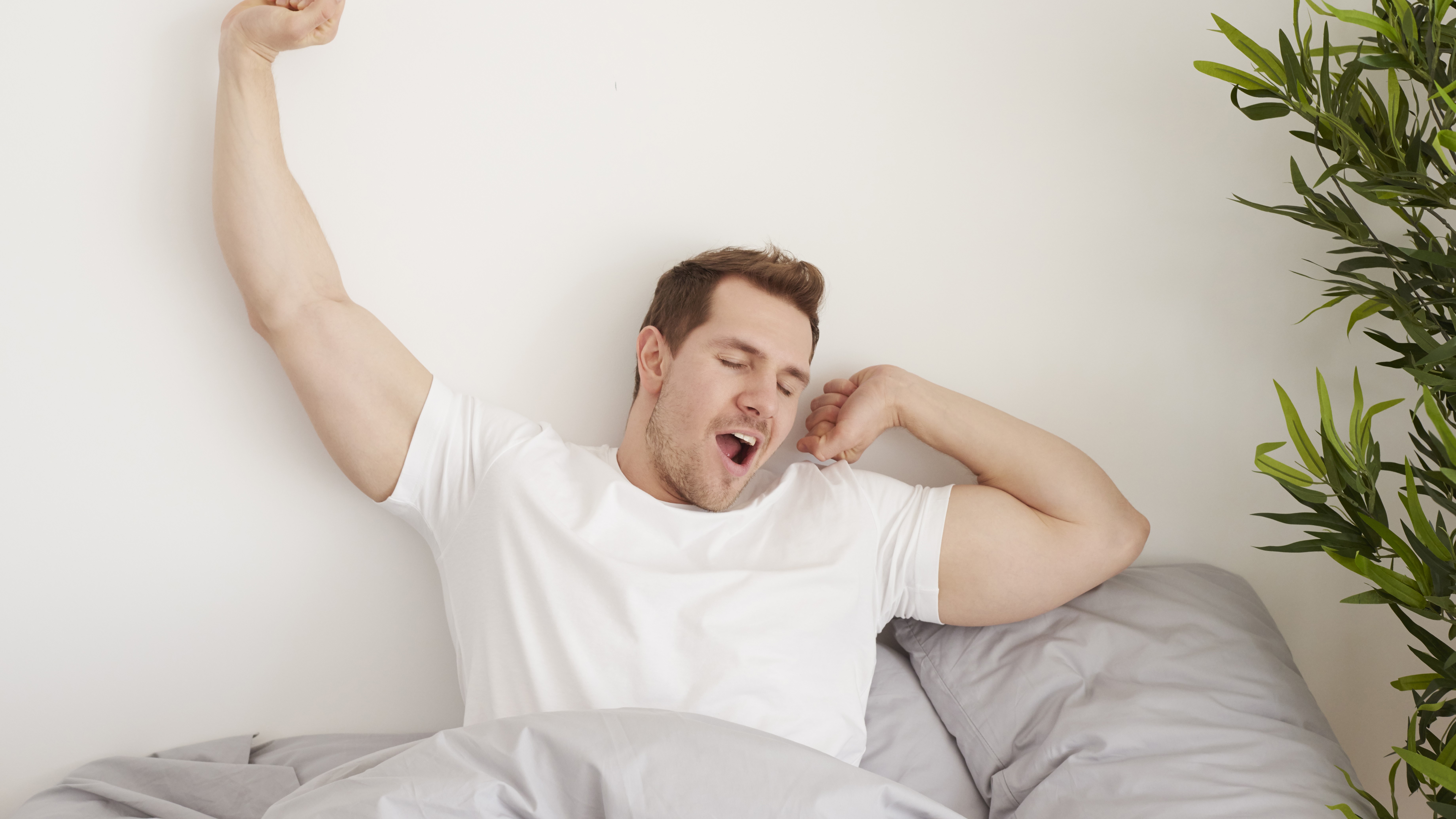 Мужчина тянется и лениться вставать с кровати