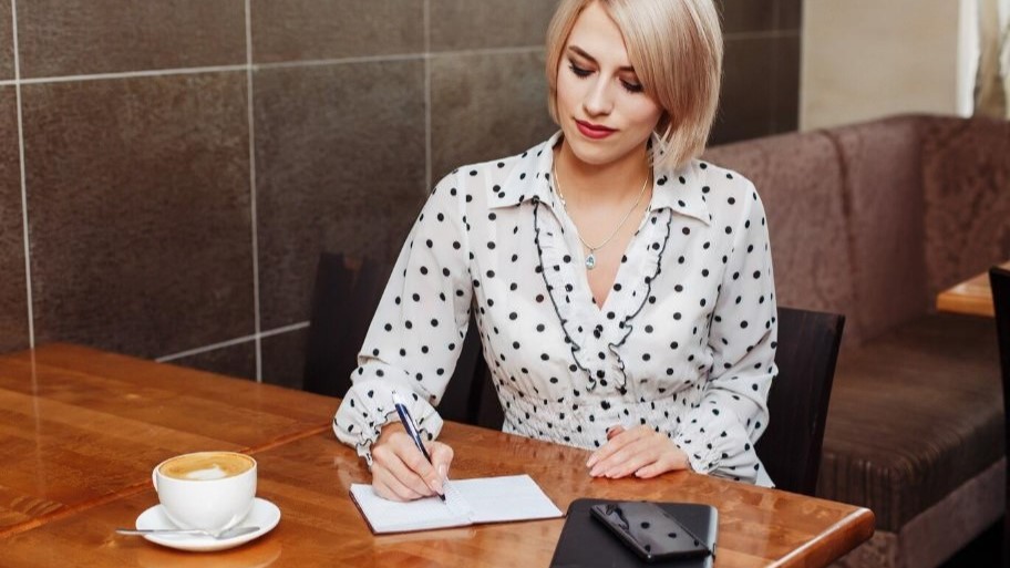 Успешная и красивая женщина в расцвете сил делает запись в блокноте