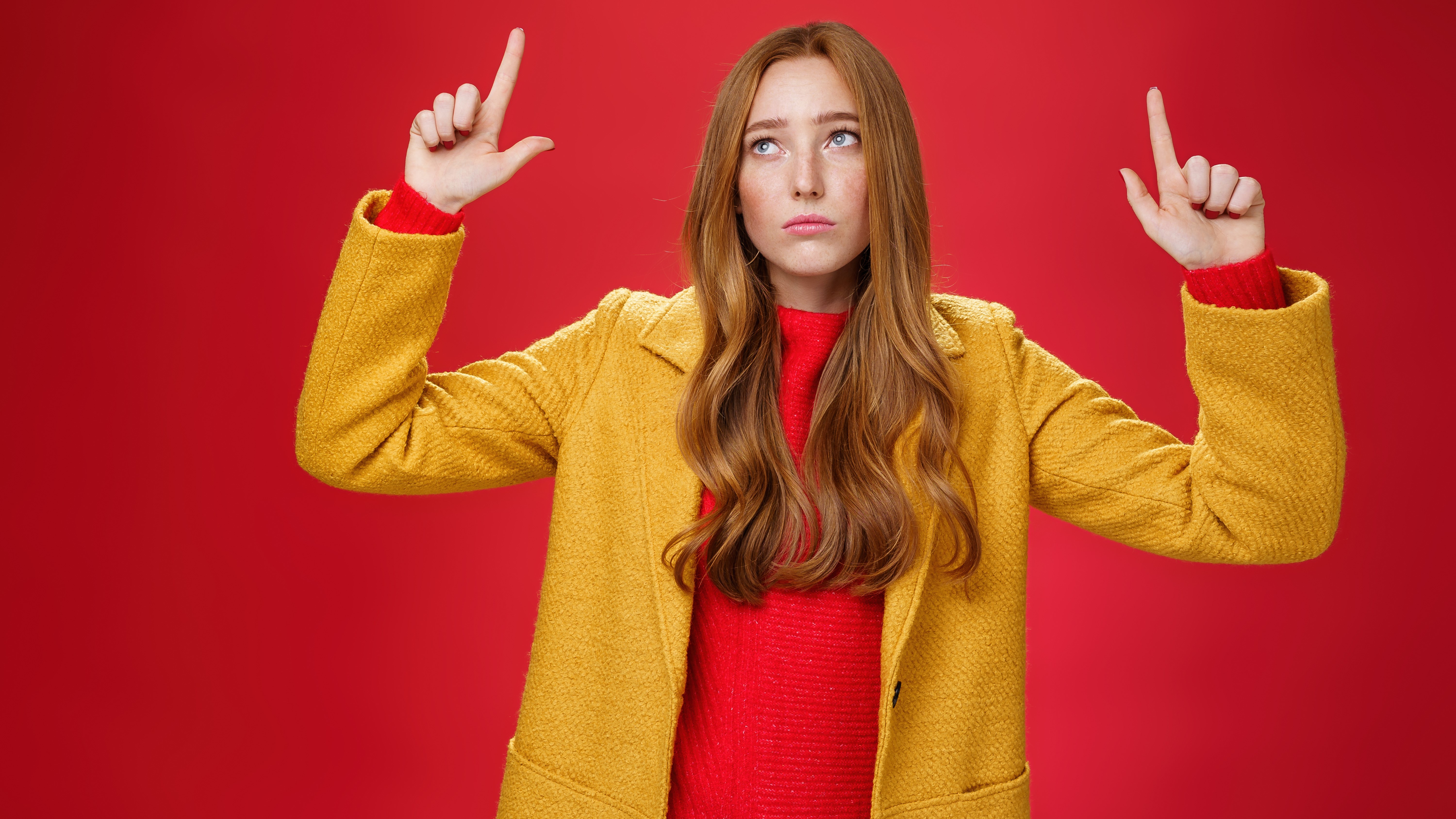 Грустная и печальная милая рыжая женщина в желтом пальто