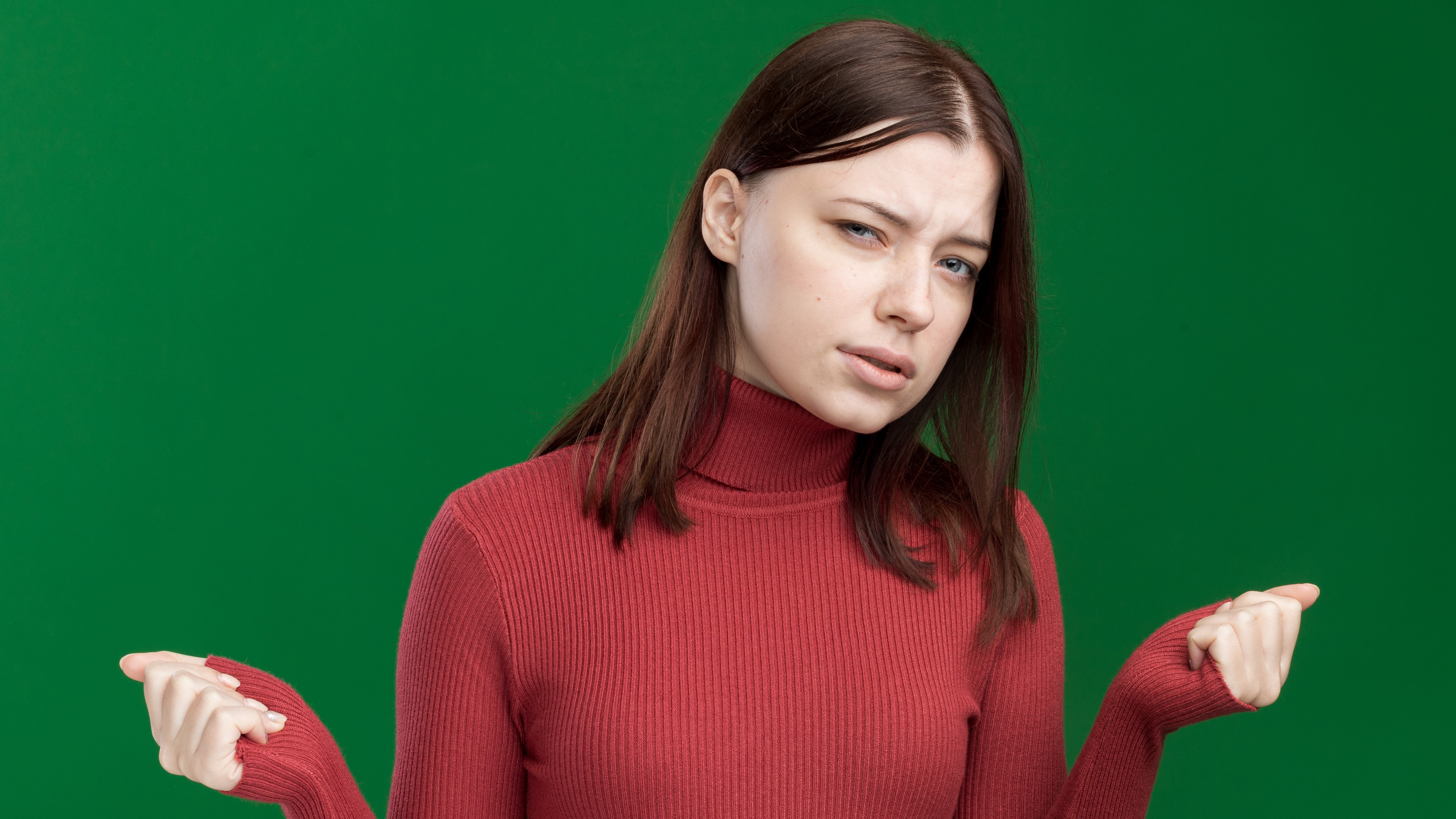 Сомнительная молодая красивая девушка со сжатыми кулаками